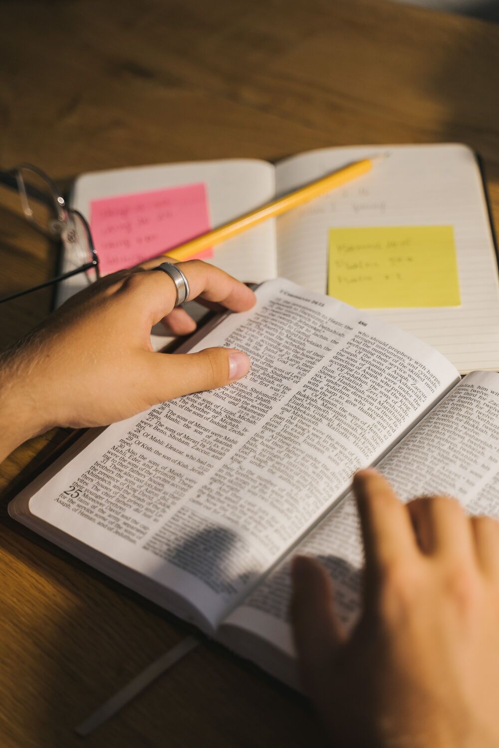 Hands turning the pages of a book next to a notebook with sticky notes